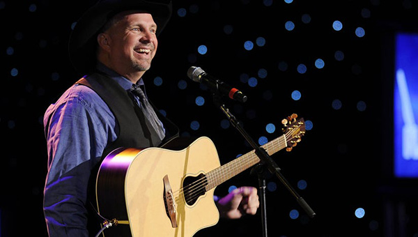 Garth Brooks smiling while holding his guitar